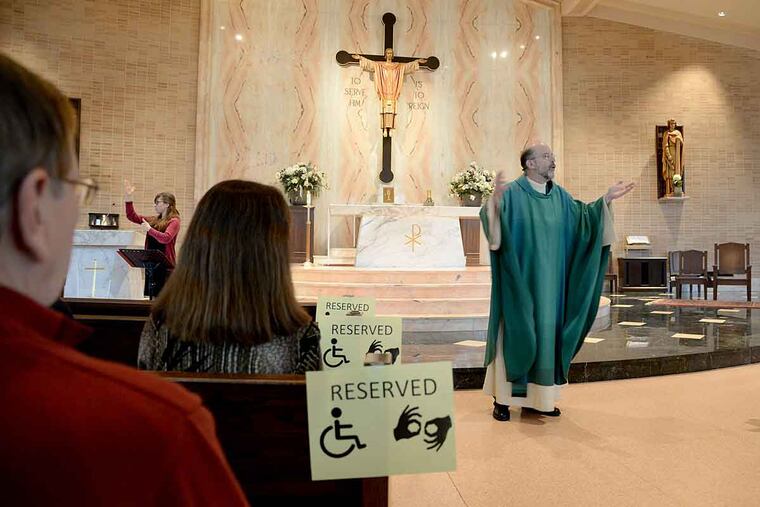 St. John Chrysostom Church pastor the Rev. Edward J. Hallinan delivers his sermon as American Sign Language interpreter Sarah Carrie (left) signs for the congregation. The church incorporates people with disabilities into the life of the congregation.