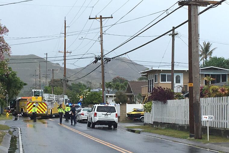 Police and firefighters respond to the scene of a helicopter crash in a residential neighborhood of Kailua, Hawaii, Monday, April 29, 2019. Fire and pieces of helicopter rained from the sky Monday in a suburban Honolulu community in a crash that killed three people aboard, officials and witnesses said. (AP Photo/Marco Garcia)