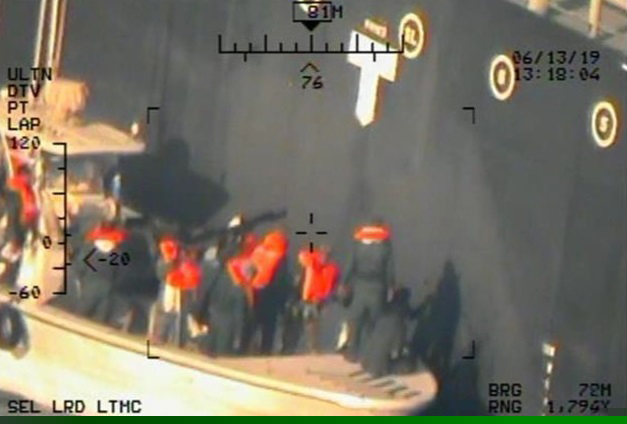 This image released by the U.S. Department of Defense on Monday, June 17, 2019, and taken from a U.S. Navy helicopter, shows what the Navy says are members of the Islamic Revolutionary Guard Corps Navy removing an unexploded limpet mine from the M/T Kokuka Courageous. (U.S. Department of Defense via AP)