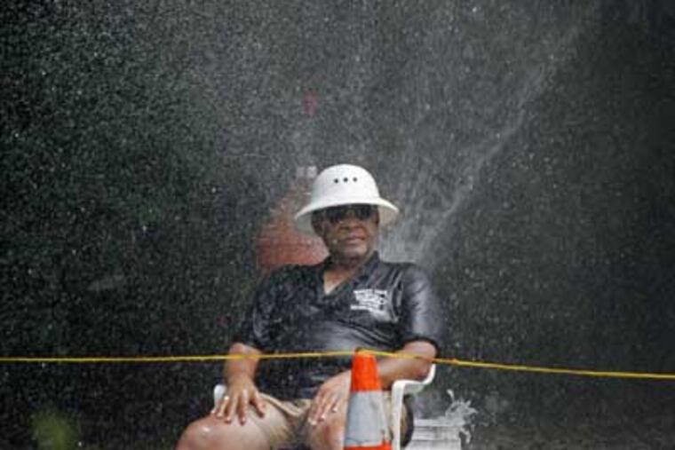 William Robbins, 71, of Southwest Philadelphia keeps cool Friday under the mist of an open fire hydrant at 46th and Paschal Ave.