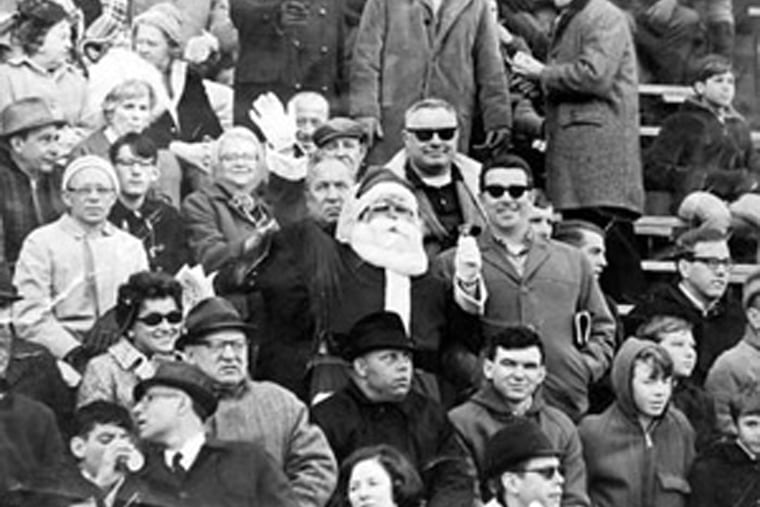 Shown in this 1967 copy photograph is Eagles fan Frank Olivo, center, wearing his Santa suit in the stands of an Eagles game at Franklin Field in 1967. Olivo was the Santa who was booed and dodged snowballs during halftime at a 1968 Eagles game.