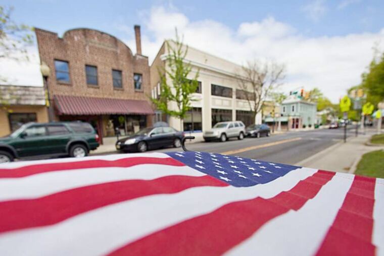A flag waves from the Merchantville Police Department sign, along West Park Avenue. While property taxes are high, residents note the borough has its own police and fire services. (David M Warren / Staff Photographer)