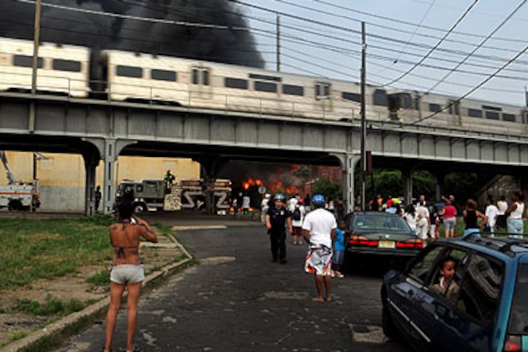 PATCO highspeed line train passes fire scene in South Camden on Thursday, June. 9, 2011, as neighborhood residents come out to watch firefighers. (Tom Gralish / Staff Photographer)