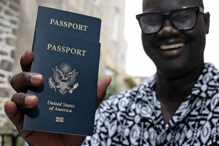 James Deng displays his and his son’s passport at his home in Philadelphia. It took three months to get the passports.