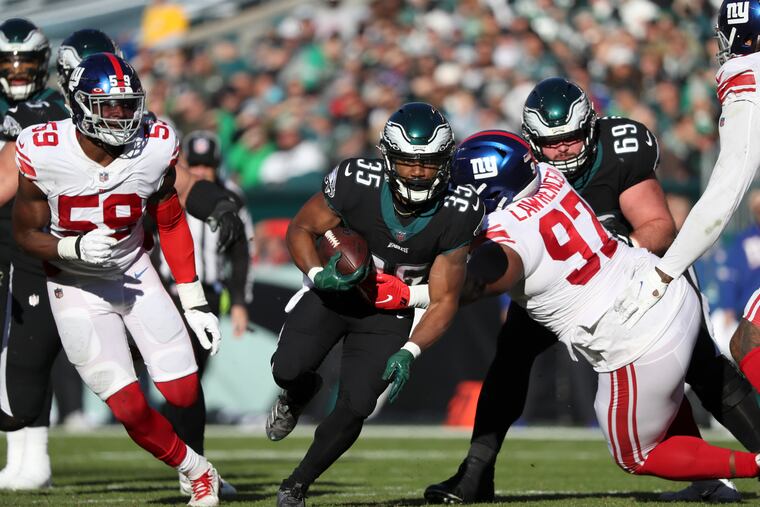 Eagles running back Boston Scott runs with the football against New York Giants defensive tackle Dexter Lawrence (right) and outside linebacker Lorenzo Carter in the second quarter on Sunday, December 26, 2021 in Philadelphia.