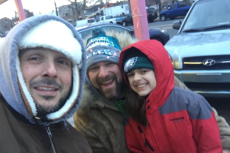 Teddy Munz, (left) 38, of Blackwood, N.J., kept a promise to get a tattoo of Nick Foles if the Eagles won the Super Bowl. He attended Thursday's parade with friends.
