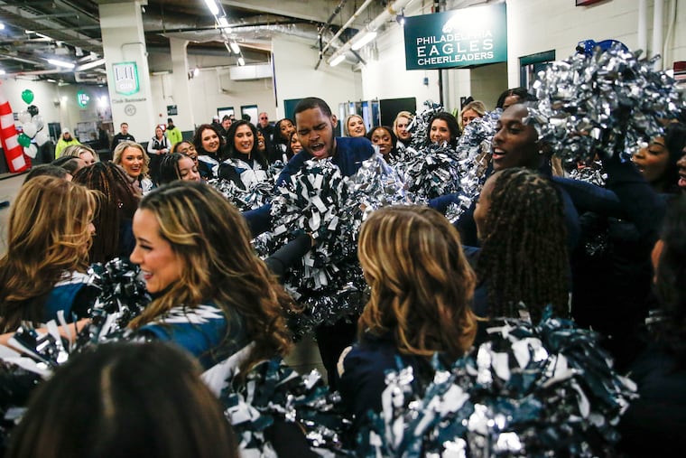 Roland Williams, center, breaks down the huddle between the George Washington High School cheer team and the Philadelphia Eagles Cheerleaders after they performed together at halftime of the Eagles NFL game between the New Orleans Saints at Lincoln Financial Field in South Philadelphia on Sunday, Jan. 1, 2023.