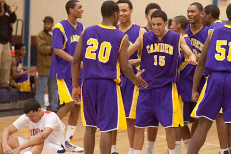 Camden teammates celebrate their 75-74 victory in South Jersey group 2 playoff action as Medford's Donte Martinez, left, reacts to the loss. (Ed Hille / Staff Photographer)