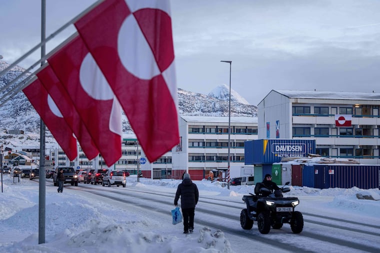 A man rides by on a quad bike past a row of Greenlandic national flags in Nuuk, Greenland.
