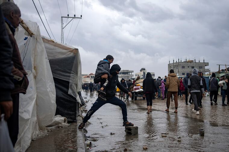 Palestinians displaced by the Israeli air and ground offensive on the Gaza Strip walk through a makeshift tent camp in Rafah on Jan. 27, 2024. The tent camps stretch for more than 10 miles along Gaza’s coast, filling the beach and sprawling into empty lots, fields and town streets.