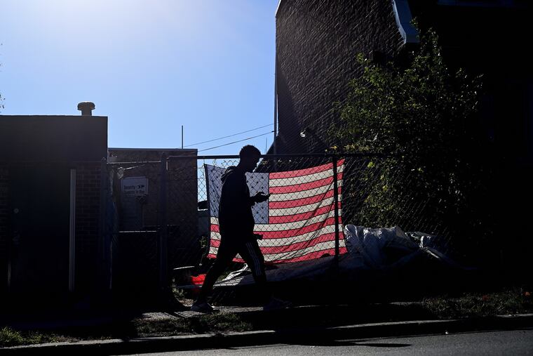 A pedestrian using a smartphone walks past an illuminated U.S. flag in Philadelphia the day before the midterm general election Monday.
