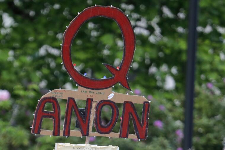 A person carries a sign supporting QAnon at a protest rally in Olympia, Wash.