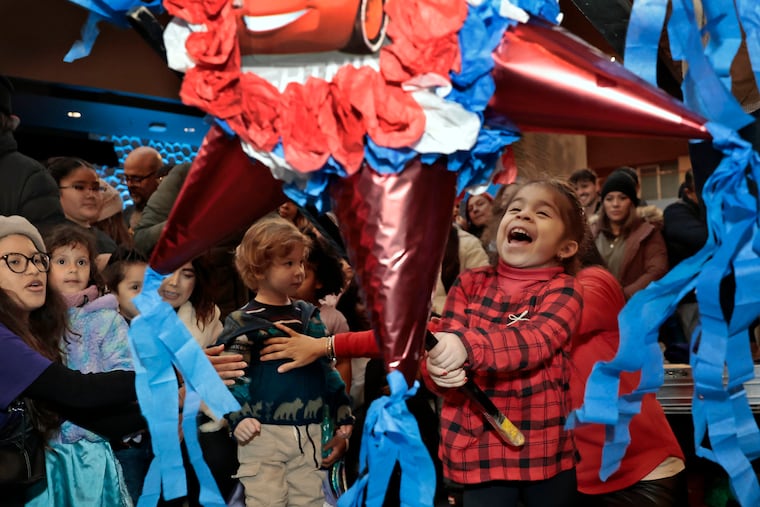 Four year old Alianna Vera of Baltimore takes great delight in the breaking of the piñata’s during “Three Kings’ Day” at the Kimmel Center in Philadelphia, on Saturday, Jan. 6, 2024.