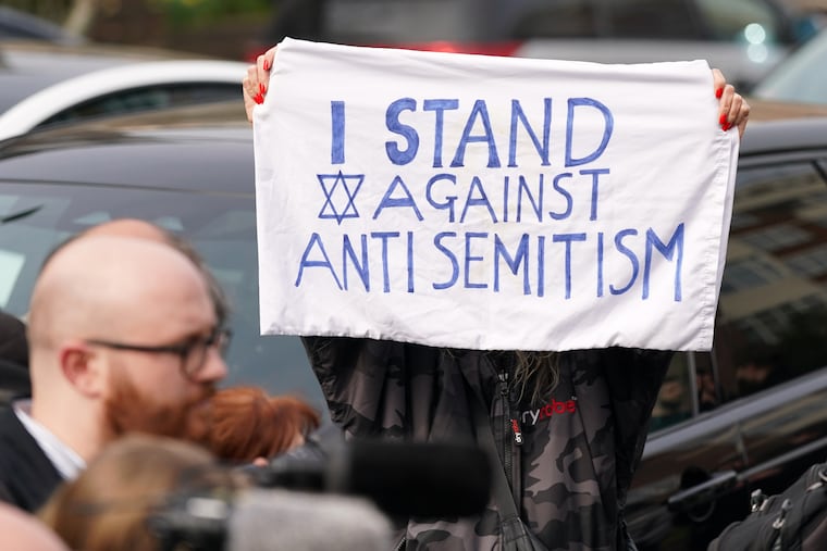 A protester displays a banner in London in March after an apparent arson attack on four vehicles belonging to a Jewish ambulance service.