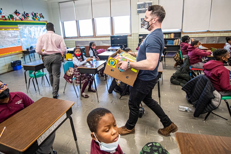 Military veteran James Morris delivers books to a class at the St. Raymond of Penafort School. Some books in its library are over 50 years old.