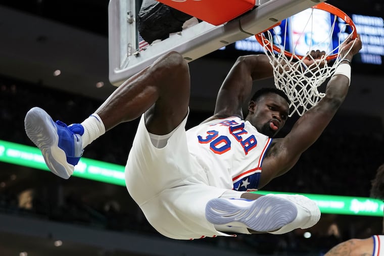 Sixers' Adem Bona hangs on the rim after dunking during the first half of a matchup against the Milwaukee Bucks on Jan. 19.