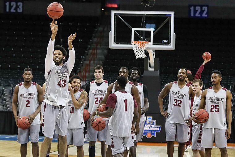Saint Joseph's forward DeAndre Bembry shoots a half court shot with
teammates during practice.