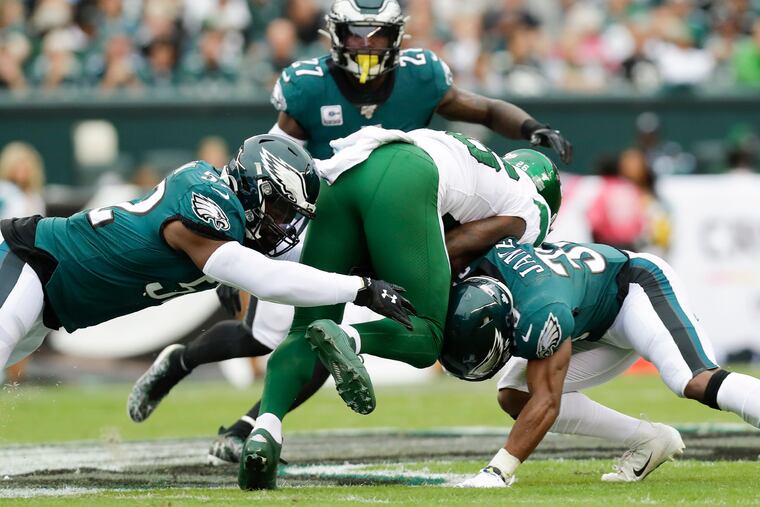 Eagles ilinebacker Zach Brown (left) and defensive back Craig James stop New York Jets running back Le'Veon Bell in the first quarter.