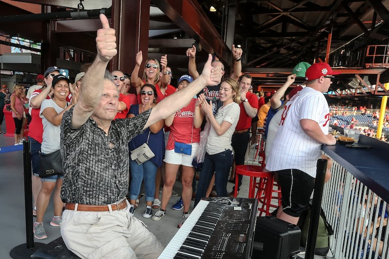 The organist George Akerley responds to the crowd at Citizens Bank Park after playing a triumphant version of "Take Me Out to the Ball Game" during "Throwback Thursday" at a Phillies doubleheader last week.
