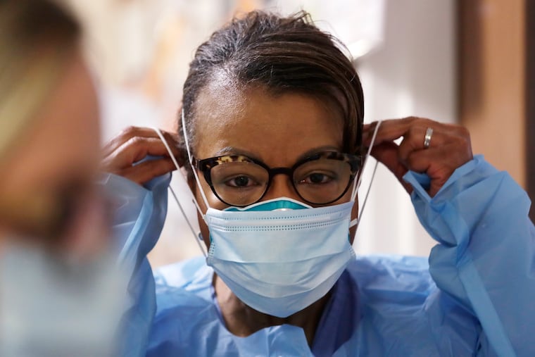 In this May 2020 photo, a respiratory therapist pulled on a second mask over her N95 mask before adding a face shield as she got ready to go into a patient's room in the COVID-19 Intensive Care Unit at a hospital in Seattle.
