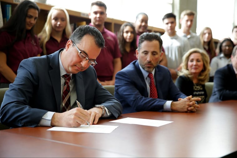 Founding board member Peter Sciortino, left, signs the lease at Holy Cross Academy in Delran, NJ on May 1, 2018. Officials with the Holy Cross Academy and the Diocese of Trenton hold a news conference to a sign a lease turning over the school to its new operators: an alumni board comprised of business leaders beginning July 1. Earlier this year, the Diocese announced plans to close the only Roman Catholic High School in Burlington County.