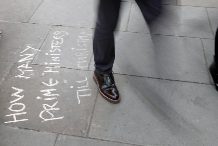 People walk past markings by protestors on the pavement opposite the Houses of Parliament in London, Monday, Sept. 9, 2019. British Prime Minister Boris Johnson voiced optimism Monday that a new Brexit deal can be reached so Britain leaves the European Union by Oct. 31.