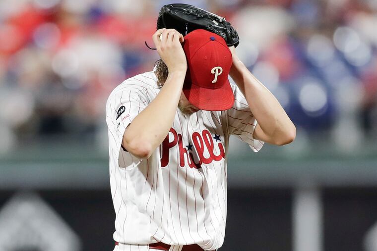 Aaron Nola puts his hands on his head after giving up a second-inning RBI single to Atlanta's Ozzie Albies on Monday.