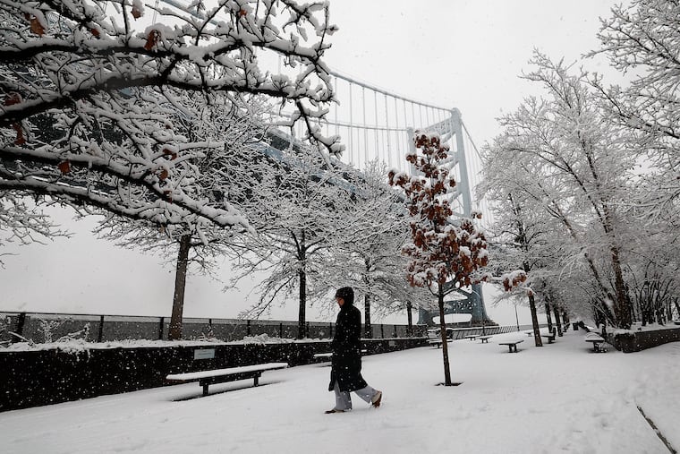 A pedestrian walks along the Race Street Pier as snow falls on Sunday, December 14, 2025