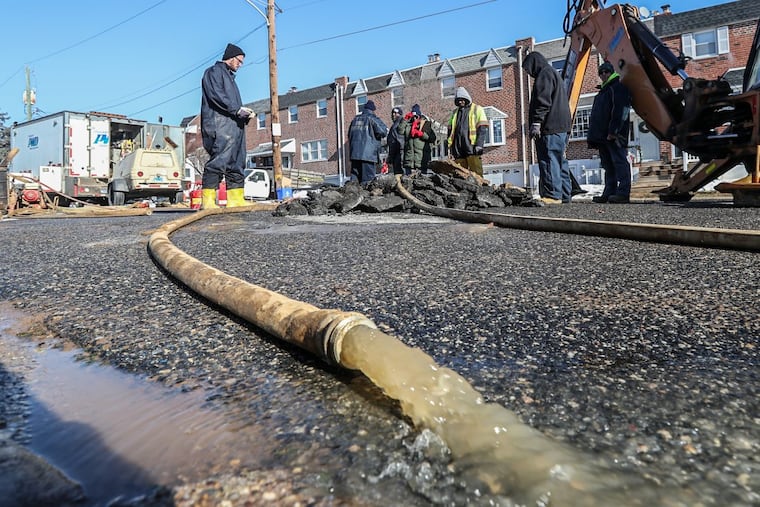 Philadelphia Water Department workers pump the water out of the hole where an 8 inch water main pipe burst early Tuesday morning flooding at least 4 homes on Minden Road in the Northeast. MICHAEL BRYANT/ Staff Photographer