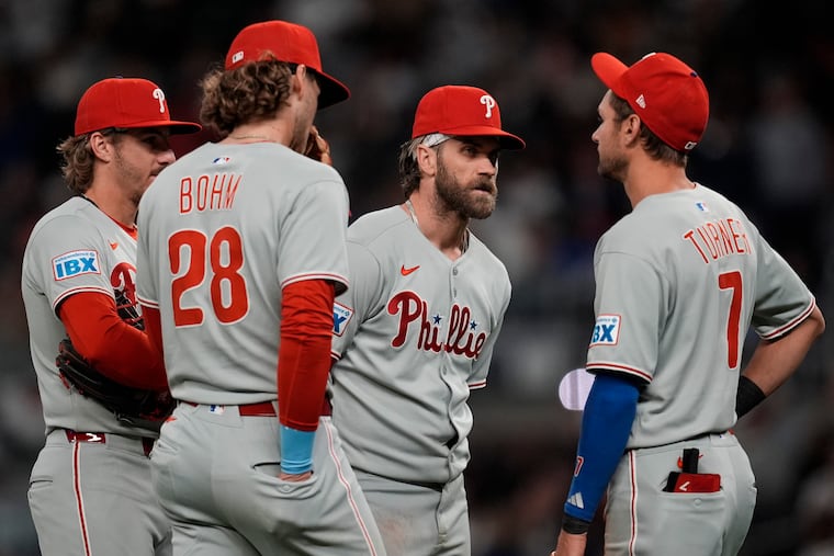The Phillies' Alec Bohm, Bryson Stott, Bryce Harper, and Trea Turner confer during the sixth inning of their 7-5 loss to the Braves in Atlanta.
