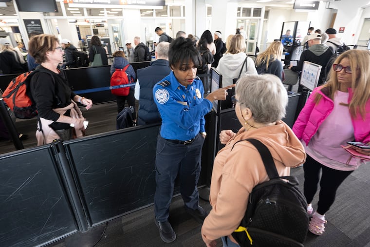 TSA agent Kelly Jonson assists a traveler through a busy security line at Gate Section B at Philadelphia International Airport on Wednesday, March 18, 2026. All but one security checkpoint at PHL is open after TSA agents started receiving paychecks after more than a month without pay.