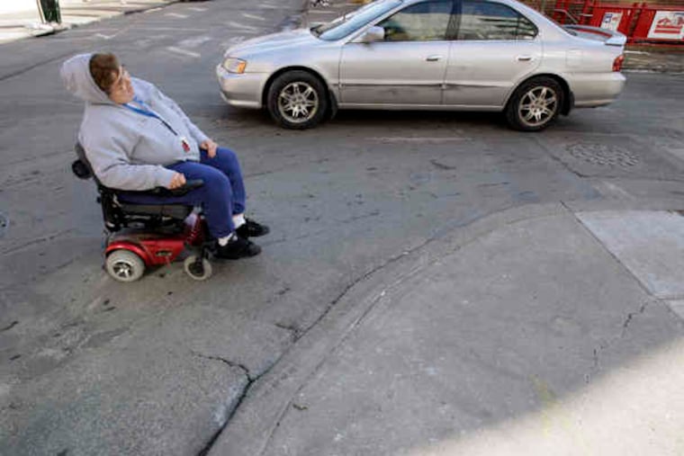 Colleen Huston, using a motorized scooter , relies on this curb cut at Ninth and Locust to reach the sidewalk. It is an older ramp with no traction surface or markings. Huston often gets stuck there when it snows.