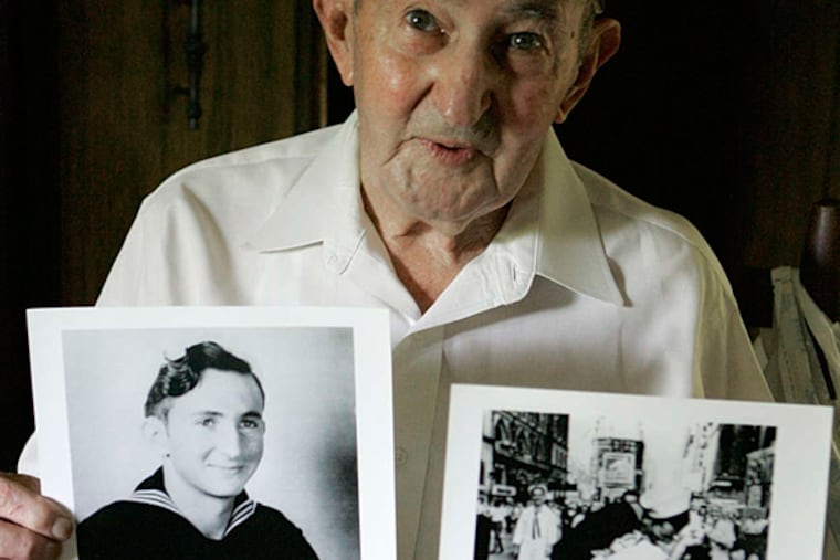 Glenn McDuffie with a portrait of himself and a copy of the iconic shot of a sailor embracing a nurse in Times Square at the end of World War II.