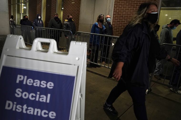 People wait in a long but brisk line as they arrive on the first day of the FEMA COVID-19 vaccination site at the Pennsylvania Convention Center in Center City Philadelphia on Wednesday, March 3, 2021.