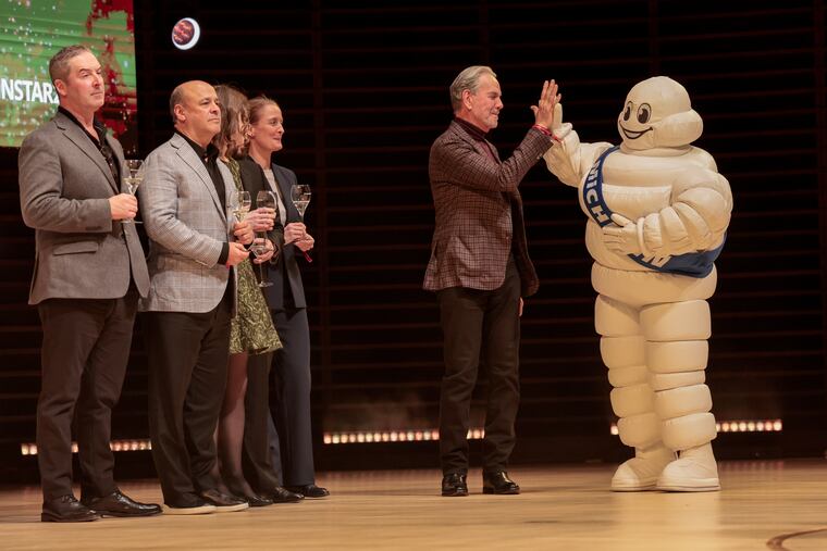 Thomas Keller high-fives the the Michelin Man during the announcements Tuesday at the Kimmel Center.