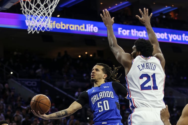 Sixers Joel Embiid tries to block Magics Cole Anthony during the 2nd quarter at the Wells Fargo Center in Philadelphia, Wednesday, January 19, 2022.