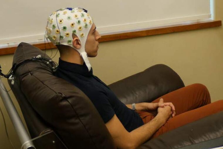 University of Washington graduate student Jose Ceballos wears an electroencephalography (EEG) cap that records brain activity and sends a response to a second participant over the Internet.