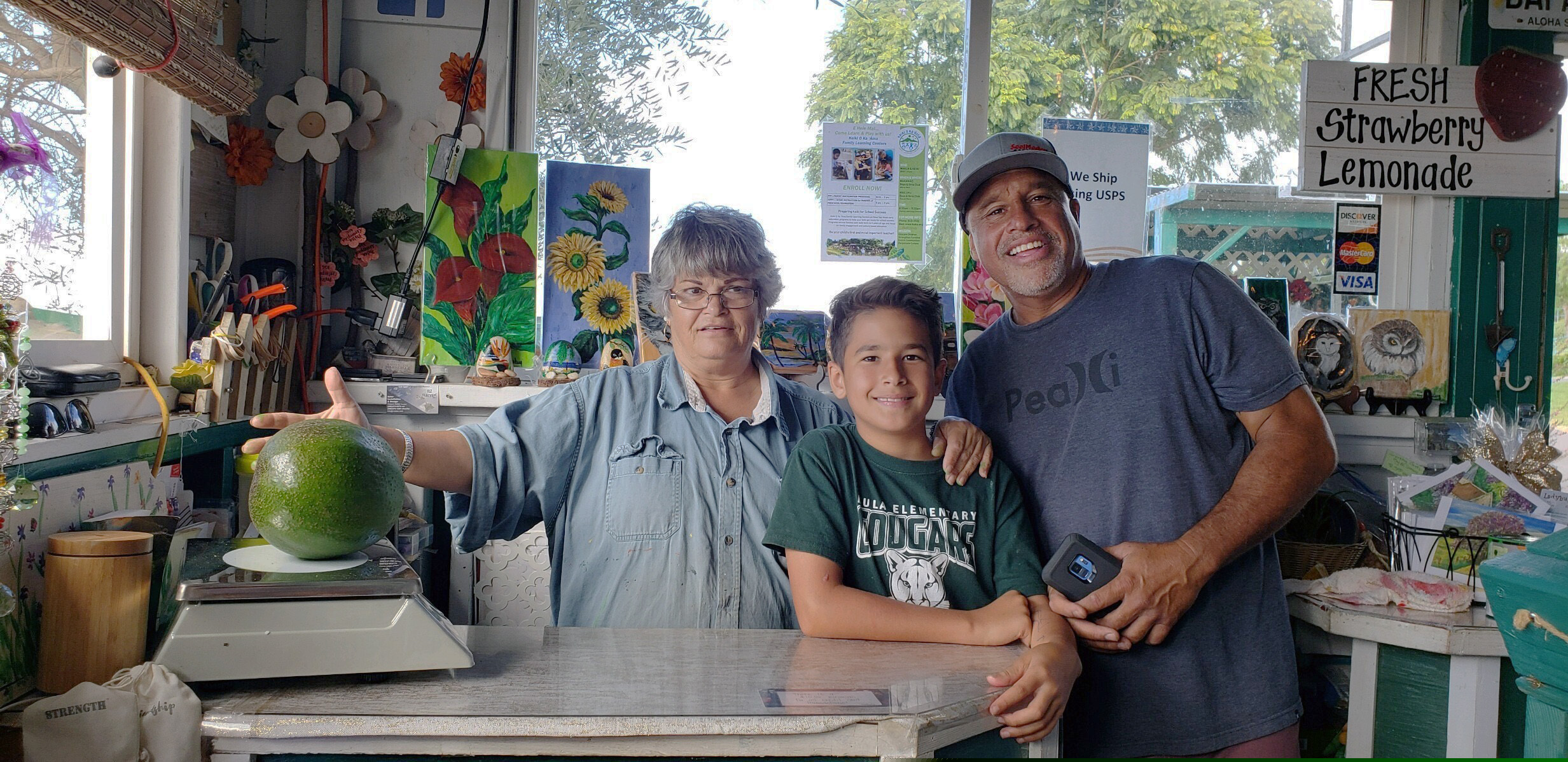 This Dec. 13, 2018 photo provided by Juliane Pokini shows the first weigh in at Kula Country Farms showing employee Meridyth Sealey, left, with Lo'ihi Pokini and his father Mark Pokini in their kitchen at Kula Country Farms in Kula, Hawaii. The Pokini family from the island of Maui received the Guinness certificate this week for the avocado weighing 5.6 pounds (2.54 kilograms), The Maui News reported Thursday, Oct. 11, 2019.