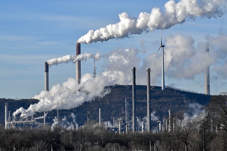 In this Jan. 16, 2020 file photo an uniper coal-fired power plant and BP refinery steam beside a wind generator in Gelsenkirchen, Germany. BP is shrinking its oil and gas business, revving up offshore wind power and developing solar and battery storage. (AP Photo/Martin Meissner)