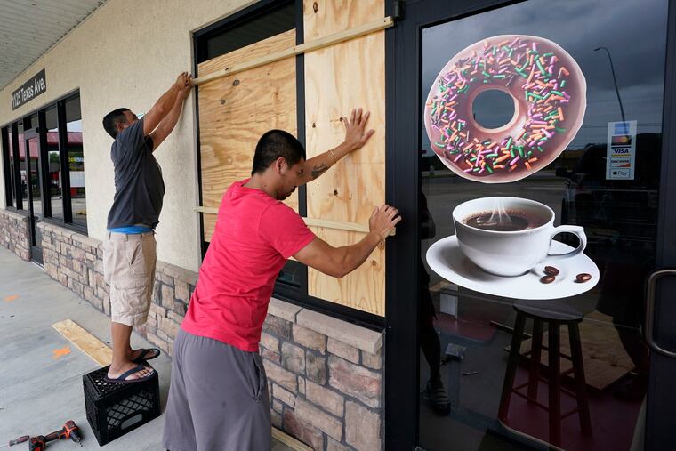 Daoith Porm, right, and Bunsant Khov, left, board their business in Bridge City, Texas, with Hurricane Laura just hours away.