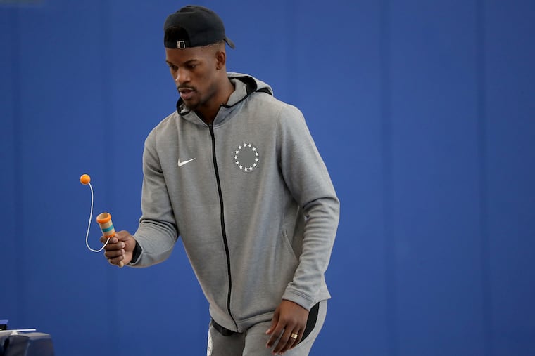 Jimmy Butler works on his eye-hand coordination with a ball and cup toy at the Sixers' practice facility in Camden on Monday.