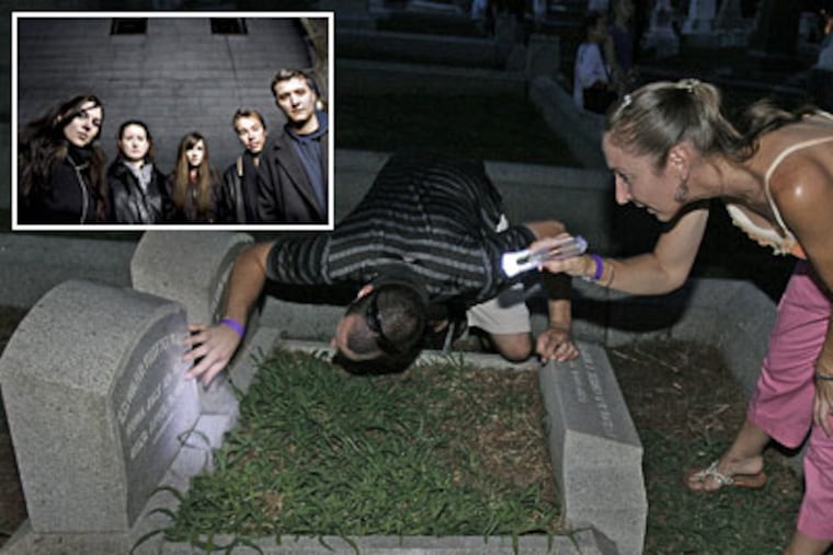 Carolyn Luther and Jeremy Schneider check a Laurel Hill Cemetery tombstone for signs of supernatural activity. Ghost-hunting has become mainstream especially with shows like Penn State's 'Paranormal State.' (Akira Suwa / Staff Photographer)