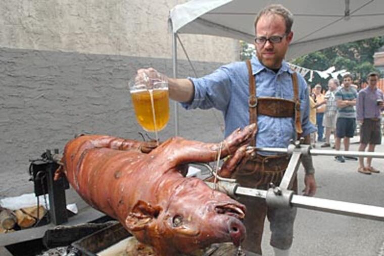 On Spring Garden Street, Jeremy Nolen pours beer on a pig on a spit. ( April Saul / Staff Photographer )