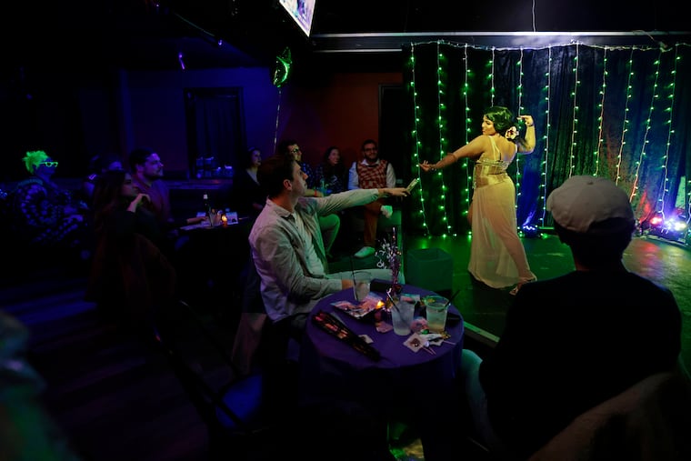 Burlesque dancer Rita Brujeria (a stage name) reaches for a tip while performing.