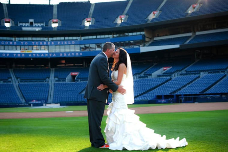 This Nov. 3, 2012 photo released courtesy of Trisha Benzine shows Nick and Trisha Benzine at their wedding held at Turner Field in Atlanta. Some couples, find that the massive stadiums where they enjoy hearing the crack of the bat can also be the perfect place to hear their beloved say, "I do." (AP Photo/Graceology Photography)