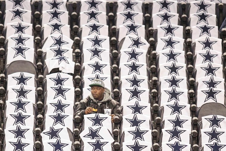 STEVEN M. FALK / STAFF PHOTOGRAPHER An Eagles fan snacks and waits for kickoff surrounded by Cowboys towels yesterday at AT&T Stadium.