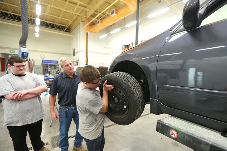 David Sandy, 19, watches as Adam Yost, 19, lifts a wheel on a 2008 Nissan Ultima they are rehabbing with teacher Mark Serfass at the Brandywine Campus of TCHS in Downingtown Tuesday October 14, 2014. ( DAVID SWANSON / Staff Photographer )