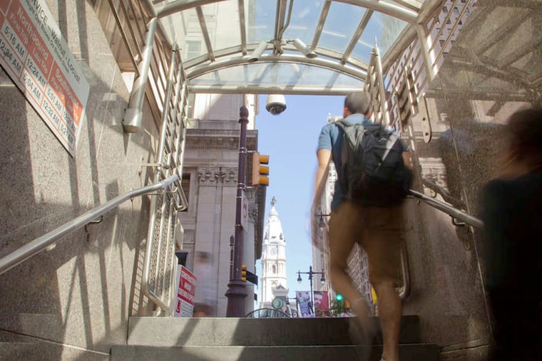A commuter emerging from a Septa station with Philadelphia City Hall in the background. The transit system offers up a poetic rhythm all its own.