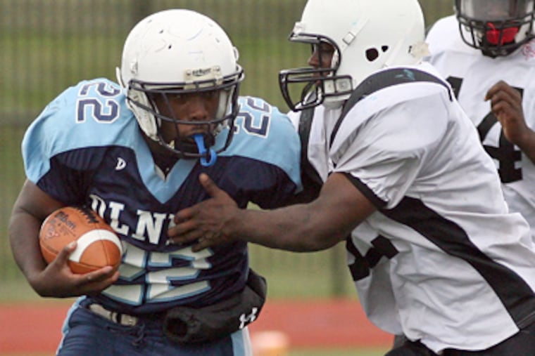 Olney High's Eric Barrow (left) carries the football against South Philadelphia High's Richard White during the third quarter of Olney's 8-6 win. (Yong Kim / Staff Photographer)