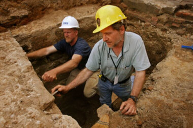 Field director Douglas Mooney (left) and archaeologist Jed Levin clean walls from what they believe may be a cellar.